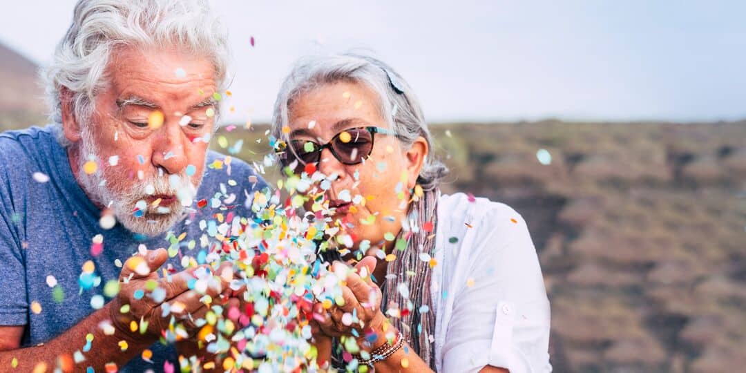 older couple blowing confetti