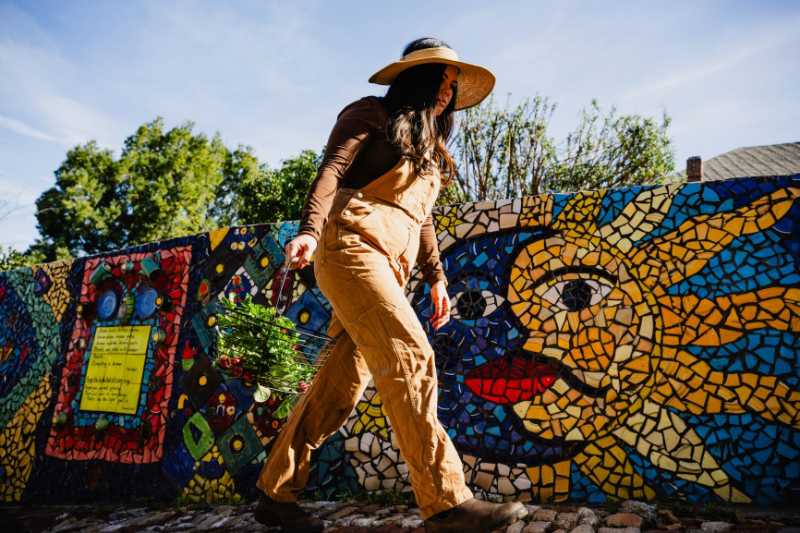 A woman walks through a garden.